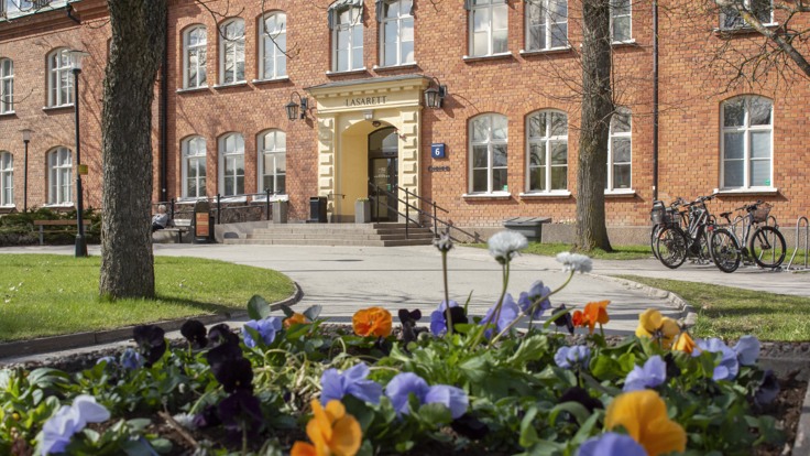 Röd tegelbyggnad med trappa, blommor i förgrunden