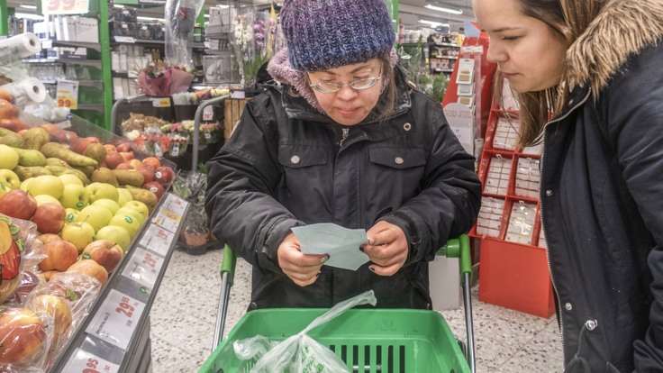 Boende och personal som tittar på en inköpslista i affären