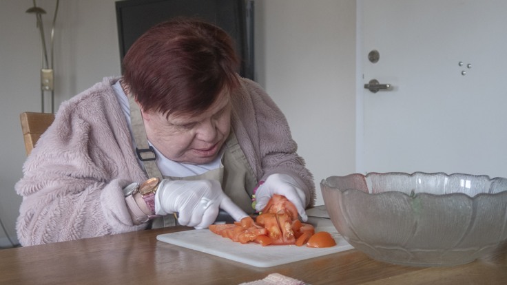 Boende som sitter vid ett bord och skär grönsaker 